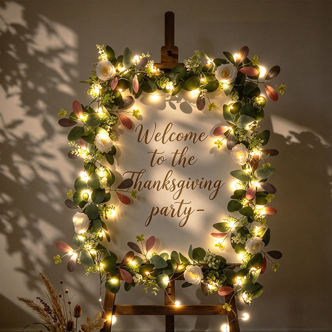 Warm-white fairy lights around a wreath-framed welcome sign