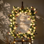 Warm-white fairy lights around a wreath-framed welcome sign